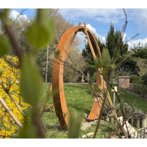 La porte de lune AGtrema en acier Corten est en train d'être mise en place et scellée dans le béton