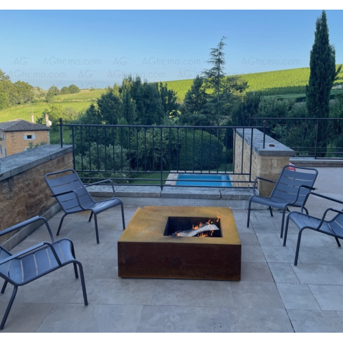 Brasero Compŏsĭtus en acier Corten en 100cm, posé sur une terrasse dans le sud, ambiance farniente